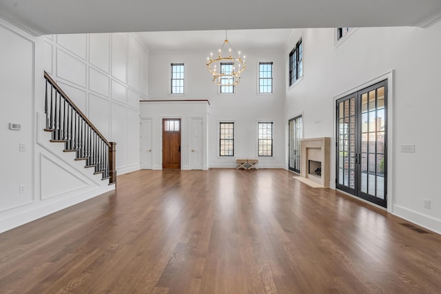 entrance foyer with dark hardwood / wood-style floors, a premium fireplace, a high ceiling, and a chandelier