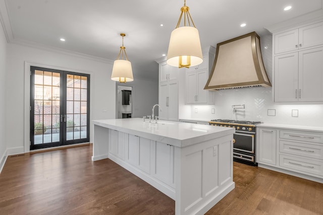 kitchen with white cabinets, custom range hood, high end stainless steel range, and pendant lighting