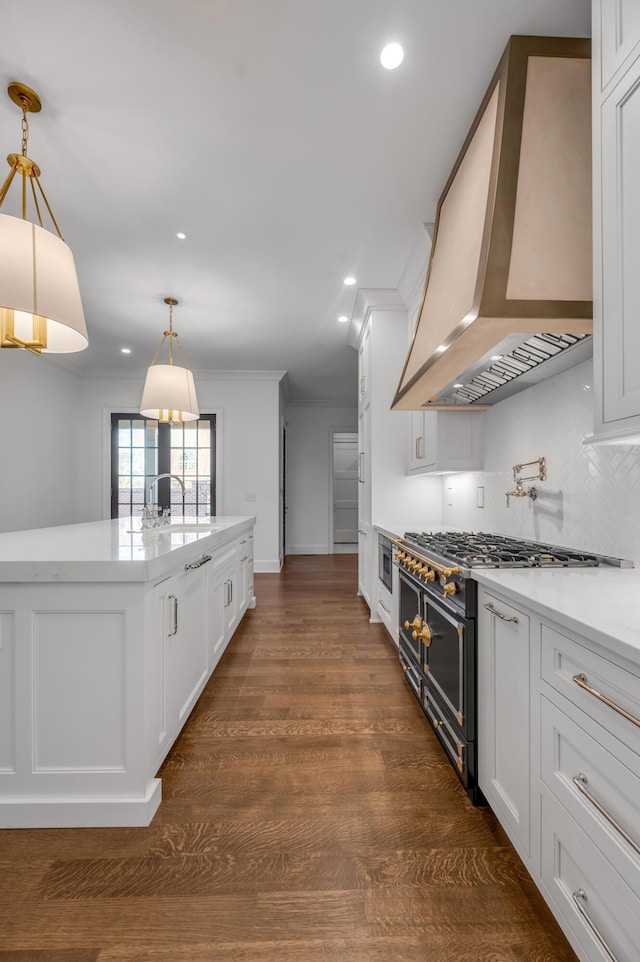 kitchen featuring decorative backsplash, stainless steel range, wall chimney range hood, white cabinetry, and hanging light fixtures