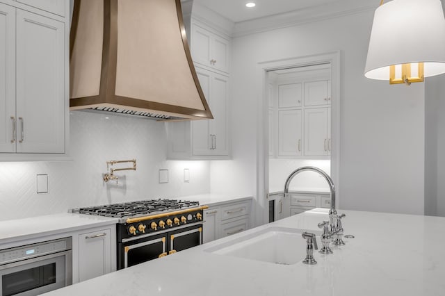 kitchen featuring stainless steel appliances, wall chimney range hood, tasteful backsplash, decorative light fixtures, and white cabinets