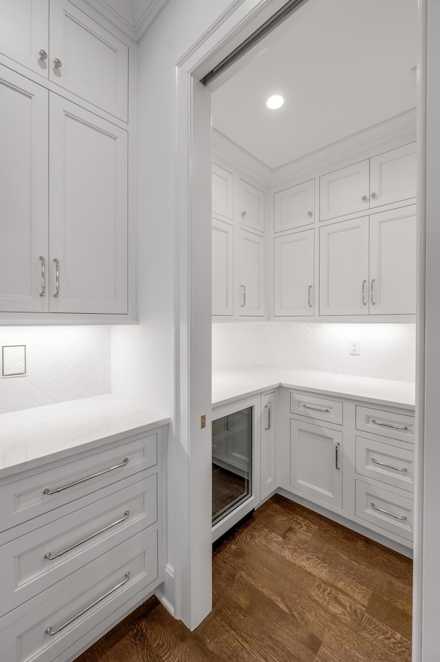 interior space with tasteful backsplash, white cabinets, beverage cooler, and dark hardwood / wood-style floors