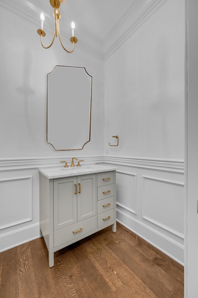 bathroom featuring a chandelier, hardwood / wood-style floors, vanity, and ornamental molding