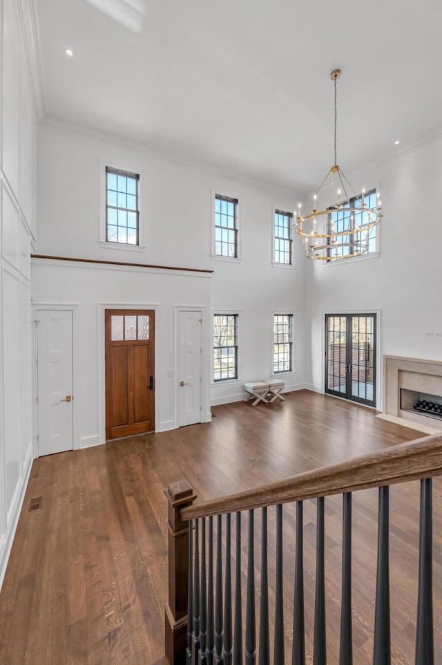 entrance foyer with french doors, ornamental molding, hardwood / wood-style flooring, a notable chandelier, and a high ceiling