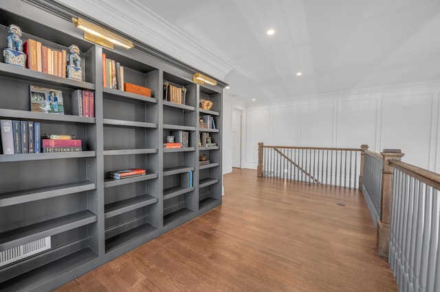 corridor featuring built in shelves, crown molding, and hardwood / wood-style flooring