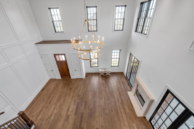 foyer entrance featuring a fireplace, hardwood / wood-style floors, a chandelier, a high ceiling, and plenty of natural light