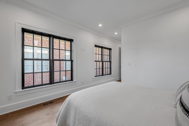 bedroom featuring multiple windows, crown molding, and hardwood / wood-style flooring