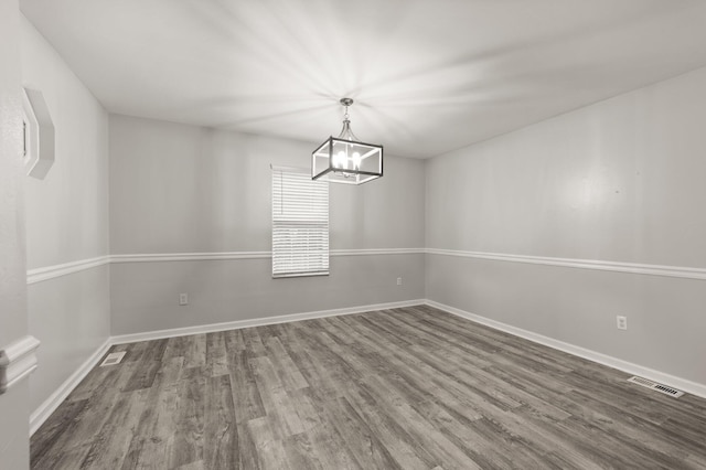 unfurnished dining area featuring dark wood-type flooring and a notable chandelier