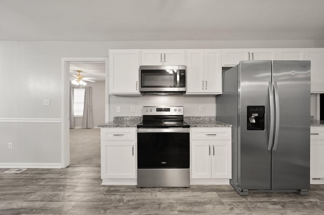 kitchen featuring dark stone countertops, white cabinetry, ceiling fan, and stainless steel appliances