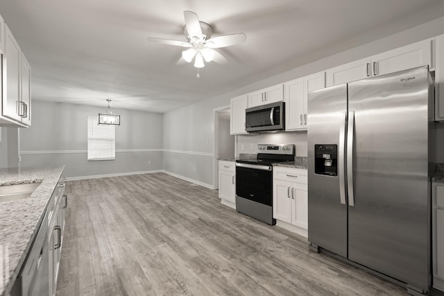 kitchen with white cabinetry, light stone counters, decorative light fixtures, and appliances with stainless steel finishes