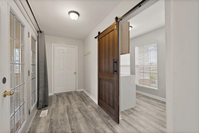 corridor with a barn door and light wood-type flooring