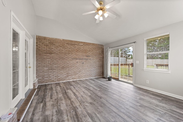 spare room featuring ceiling fan, dark wood-type flooring, brick wall, and vaulted ceiling