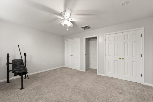 unfurnished bedroom with light carpet, two closets, and ceiling fan