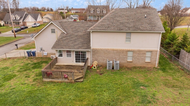 rear view of property with central air condition unit and a yard