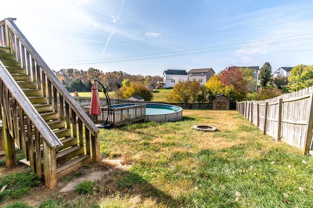 view of yard with a fire pit, a swimming pool side deck, and a storage shed