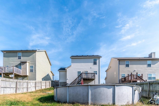 back of house with a pool side deck and a yard