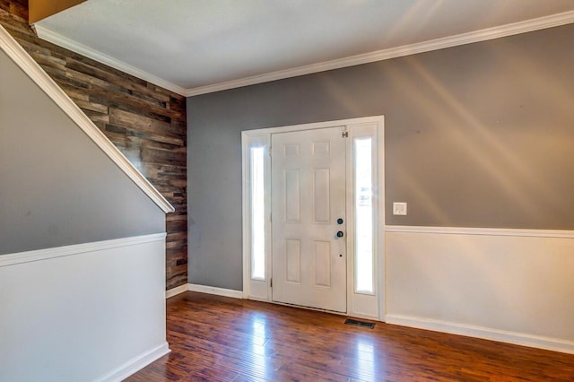 entrance foyer featuring wooden walls, dark wood-type flooring, a healthy amount of sunlight, and ornamental molding