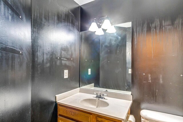 bathroom with vanity, toilet, and an inviting chandelier