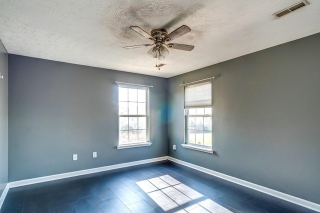 empty room with ceiling fan, dark wood-type flooring, and a textured ceiling