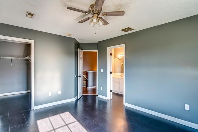 unfurnished bedroom with ceiling fan, ensuite bath, and a closet