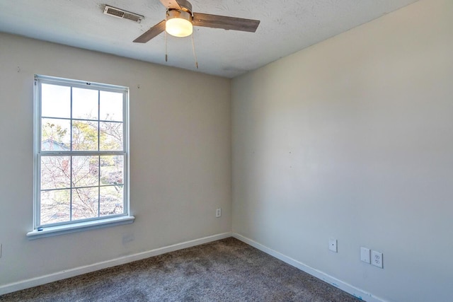 spare room with ceiling fan and dark carpet