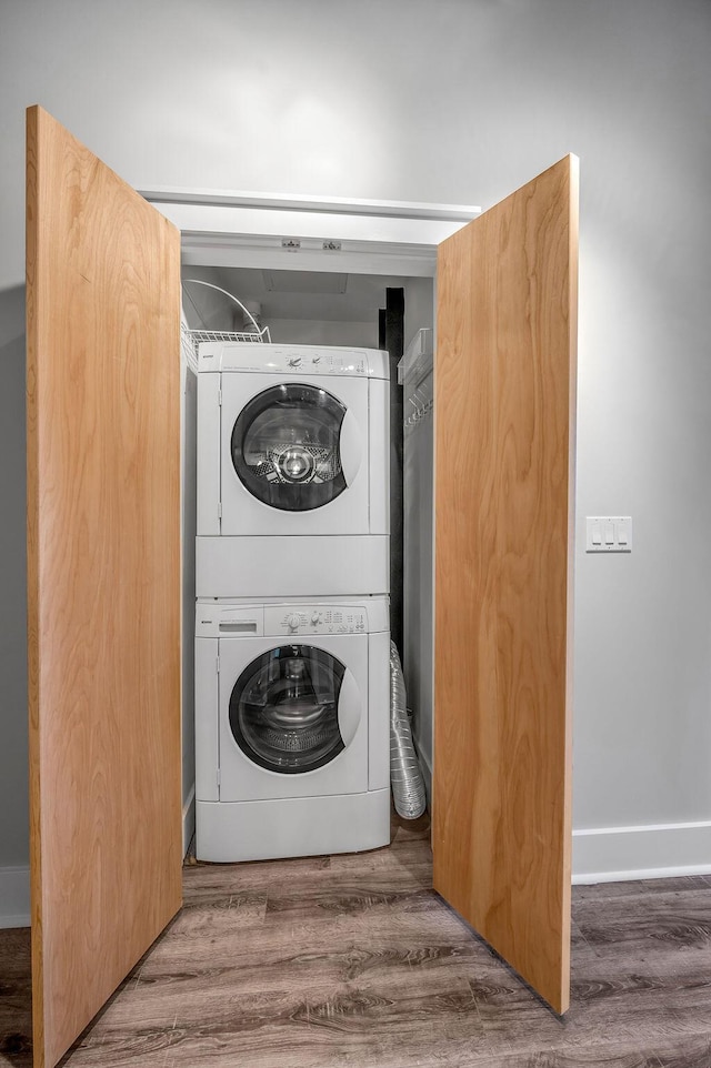 clothes washing area featuring dark wood-type flooring and stacked washer and clothes dryer