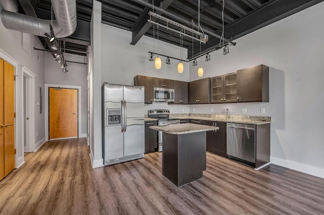 kitchen with dark brown cabinetry, a high ceiling, dark hardwood / wood-style floors, a kitchen island, and appliances with stainless steel finishes