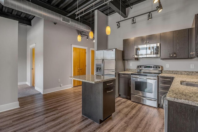 kitchen featuring a center island, a towering ceiling, hanging light fixtures, and appliances with stainless steel finishes