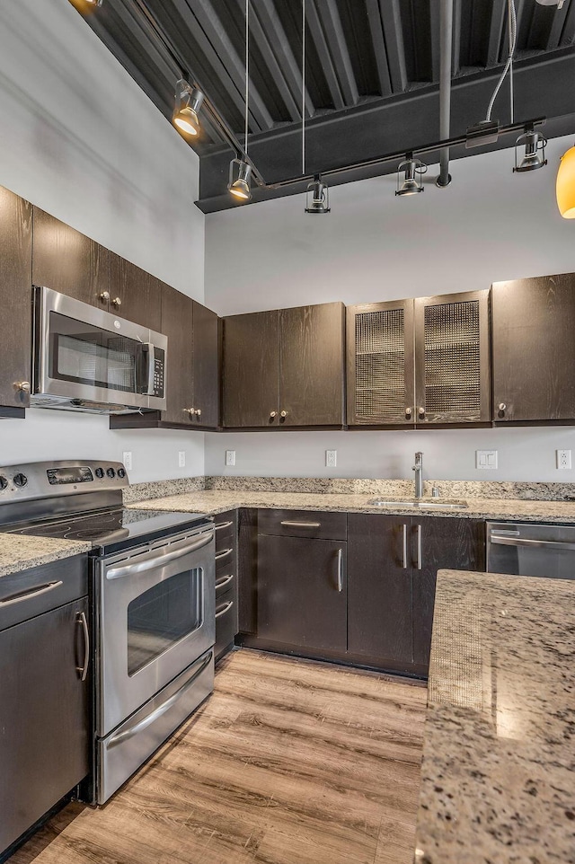 kitchen featuring dark brown cabinetry, light stone countertops, sink, and appliances with stainless steel finishes