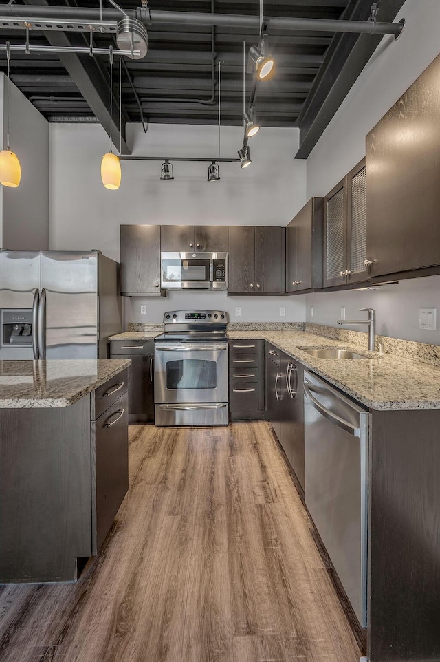 kitchen featuring dark brown cabinetry, sink, stainless steel appliances, track lighting, and decorative light fixtures