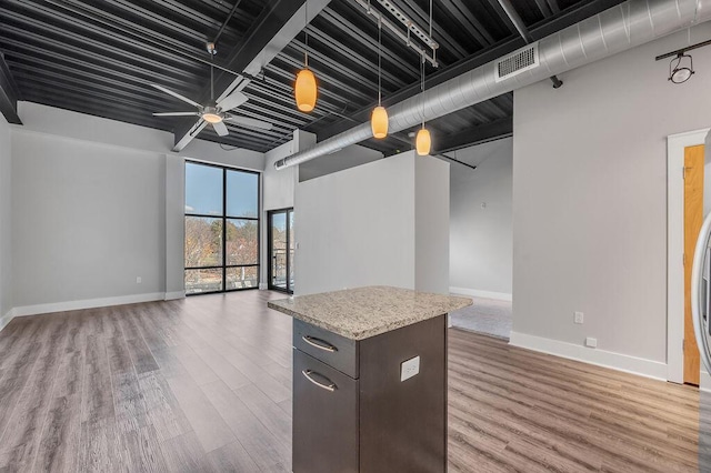 interior space with hardwood / wood-style floors, ceiling fan, a center island, and dark brown cabinets