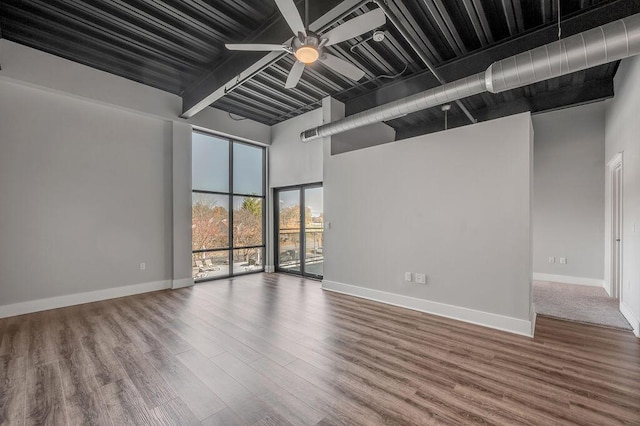 empty room with a high ceiling, ceiling fan, and hardwood / wood-style floors