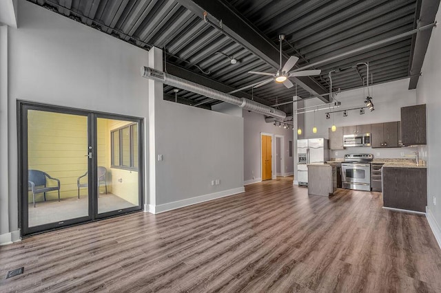 kitchen featuring ceiling fan, dark brown cabinets, a towering ceiling, and appliances with stainless steel finishes