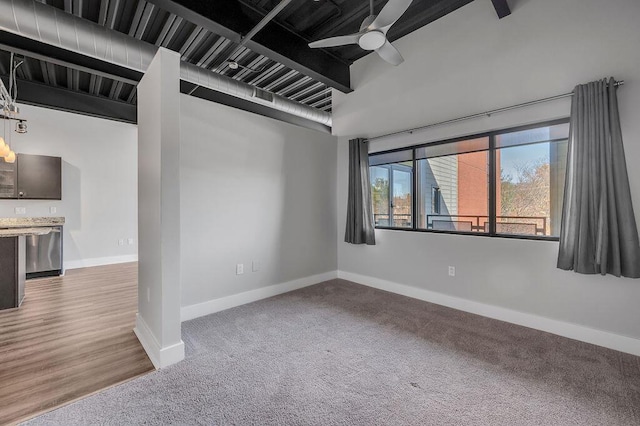 empty room with a towering ceiling, carpet floors, and ceiling fan