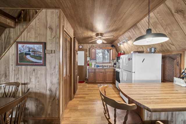 kitchen with pendant lighting, wood walls, ceiling fan, white fridge, and wood ceiling