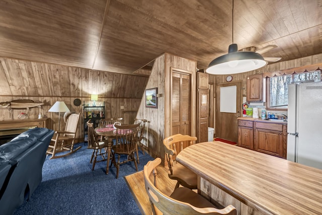 carpeted dining area with wooden ceiling, sink, and wooden walls