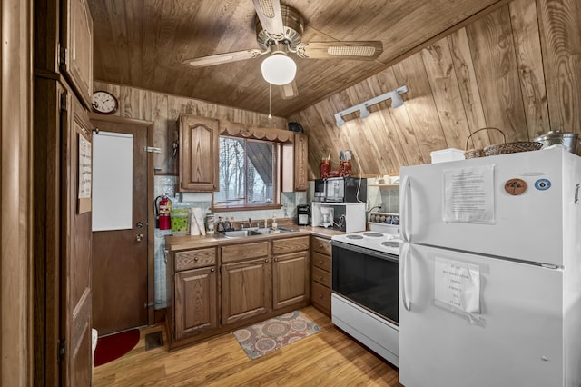 kitchen with wood ceiling, white appliances, ceiling fan, wooden walls, and sink