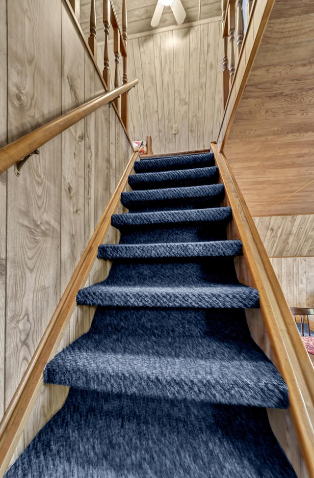 stairs with ceiling fan, wood walls, and wood ceiling