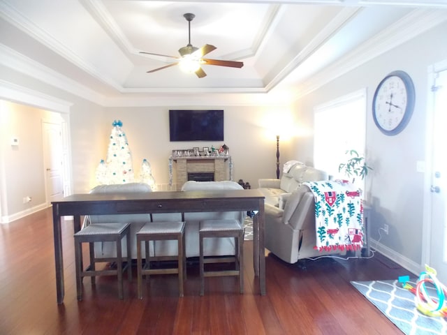 living room featuring dark wood-type flooring, ceiling fan, crown molding, and a raised ceiling