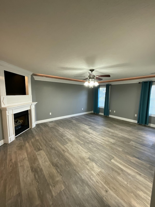 unfurnished living room with dark hardwood / wood-style flooring, ornamental molding, and ceiling fan