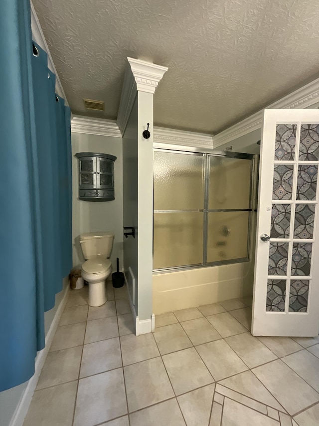 bathroom featuring toilet, shower / bath combination with glass door, tile patterned flooring, and a textured ceiling