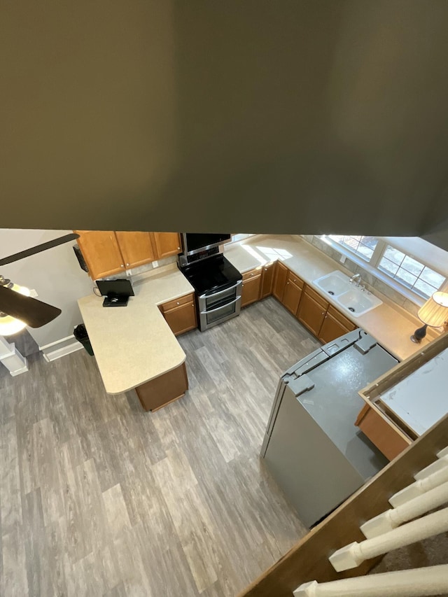 kitchen with sink, stainless steel range oven, and light hardwood / wood-style flooring