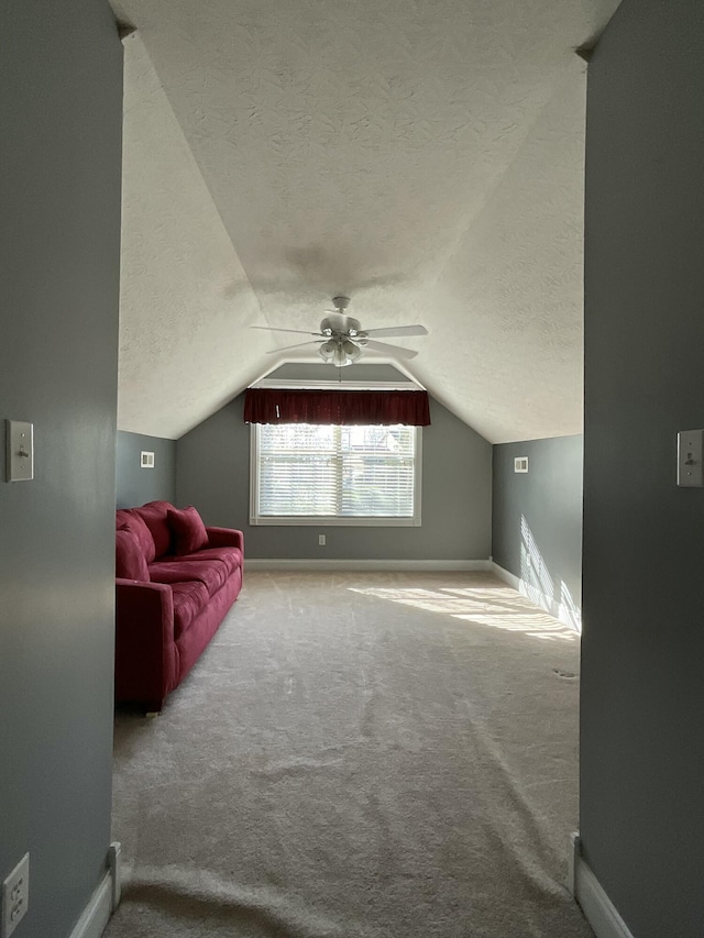 additional living space featuring vaulted ceiling, carpet, ceiling fan, and a textured ceiling