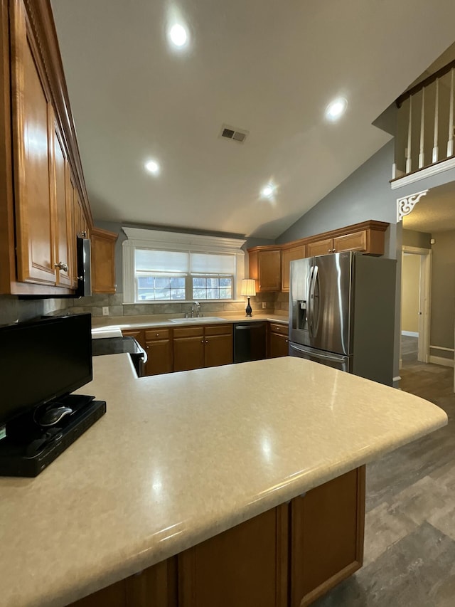 kitchen featuring sink, stainless steel fridge, black dishwasher, tasteful backsplash, and kitchen peninsula