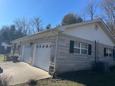 view of side of property featuring a garage and central AC unit