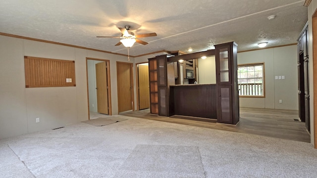 unfurnished living room with carpet flooring, ornamental molding, and a textured ceiling