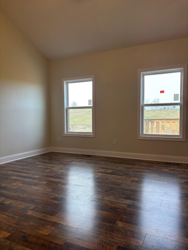 spare room with dark hardwood / wood-style flooring and vaulted ceiling