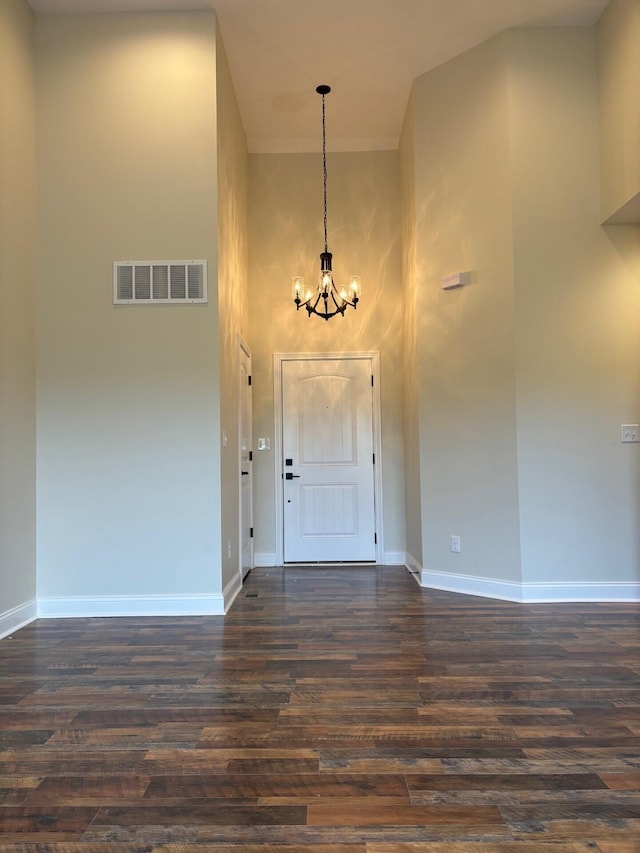 entryway with dark wood-type flooring, a high ceiling, and a chandelier