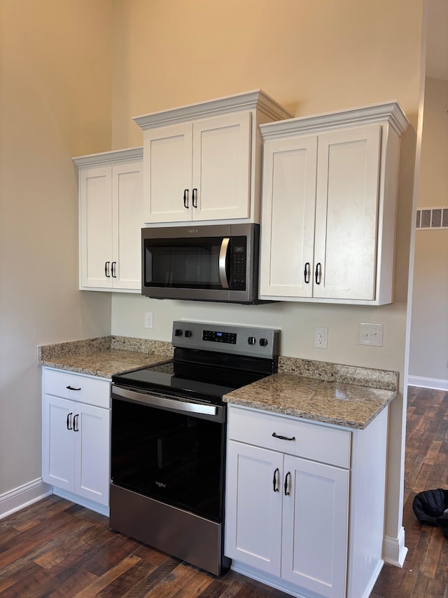 kitchen with light stone countertops, dark hardwood / wood-style flooring, white cabinetry, and stainless steel appliances