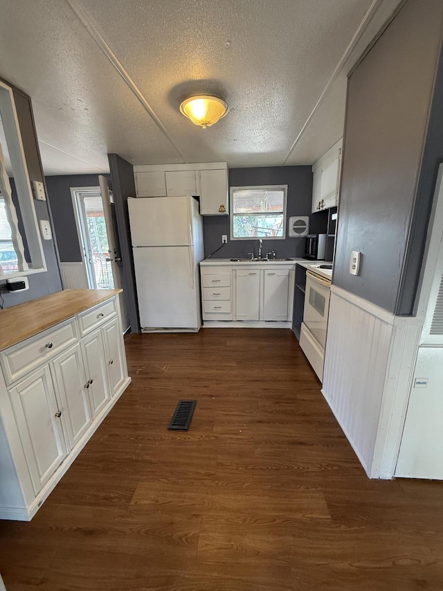 kitchen with a textured ceiling, white appliances, white cabinetry, and dark hardwood / wood-style flooring