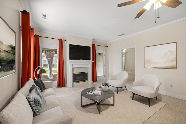 living room with ceiling fan, ornamental molding, light carpet, and a tiled fireplace